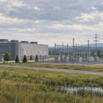 Painted illustration of a data-center building, fenced electrical substation and power lines, with homes in the distance.